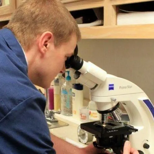 A veterinarian using a microscope to examine a specimen at the Eastview Veterinary Clinic